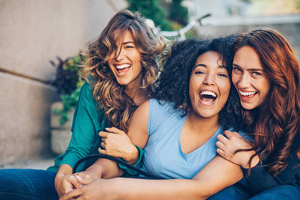 Three young women laughing outdoors Three young women laughing outdoors